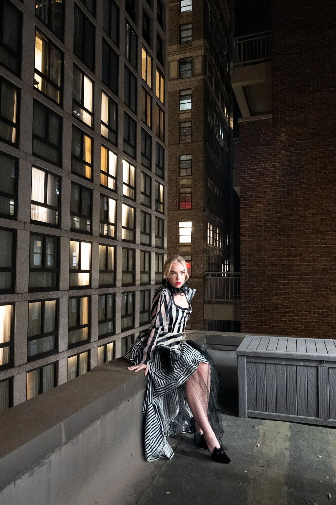 Model wearing a striped black and white evening gown on a New York terrace.